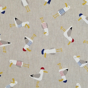 May include: A fabric featuring a repeating pattern of cartoon seagulls. The seagulls are white with grey wings, yellow beaks and legs. Some wear blue and white striped shirts, red and white striped shirts, or blue berets. The background is a light beige colour.