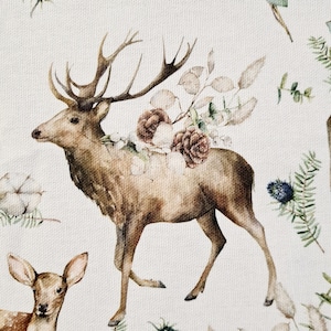 Può includere: Un'illustrazione ad acquerello di un cervo marrone con grandi corna in piedi in un campo di fiori. Il cervo è circondato da fiori bianchi, rosa e marroni. Lo sfondo è beige chiaro.