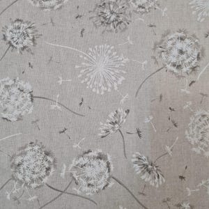 May include: A beige linen fabric with a white and gray dandelion pattern. The dandelions are scattered across the fabric and are in various stages of bloom.