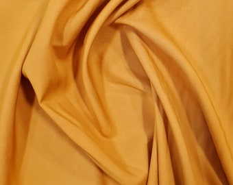 May include: A close-up of a smooth, golden yellow fabric with soft folds and wrinkles.