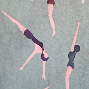 Op de afbeelding: Een groene stof met een herhalend patroon van roze figuren in zwarte badpakken die in het water duiken. De figuren zijn gestileerd en hebben een retro-uitstraling.