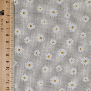 May include: A close-up of a light grey fabric with a white daisy pattern. The daisies have yellow centres.