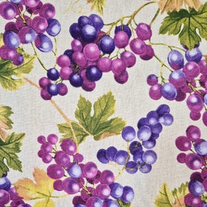 Puede incluir: Una tela con un patrón repetido de uvas moradas, hojas verdes y vides marrones. Las uvas varían en color de morado oscuro a rosa claro. Las hojas son una mezcla de verde y amarillo. El fondo es de color beige claro.