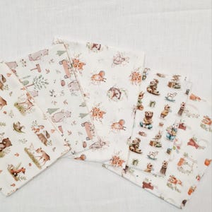 Può includere: Quattro quadrati di tessuto bianco con diverse stampe di animali del bosco. Le stampe includono orsi, cervi, scoiattoli, ricci e altre creature del bosco. Il tessuto è morbido e ha una texture delicata.