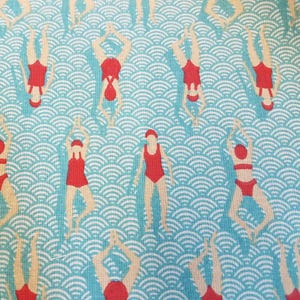 以下が含まれることがあります： 水着と赤い帽子をかぶった水泳選手の繰り返し模様。背景は水色の地に白い波模様。水泳選手は様々なポーズをとっており、逆さまになっているものもあり、ダイナミックで遊び心のあるデザインです。
