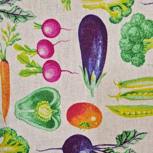 Könnte beinhalten: Stoffmuster mit farbenfrohen Illustrationen verschiedener Gemüsesorten. Das Design umfasst eine Karotte, Radieschen, eine Aubergine, eine grüne Paprika, eine Tomate, Brokkoli und Erbsenschoten. Das Gemüse ist vor einem neutralen Hintergrund angeordnet.