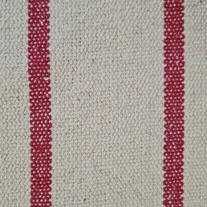 Puede incluir: Primer plano de una tela blanca con dos rayas rojas que corren verticalmente por el centro. La tela tiene una textura tejida.