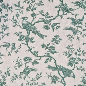 Pode incluir: Um tecido com um padrão repetido de pássaros verde-azulado pousados em ramos floridos. Os pássaros e os ramos estão sobre um fundo creme, criando um design clássico inspirado na natureza. O tecido tem uma textura semelhante à do linho.