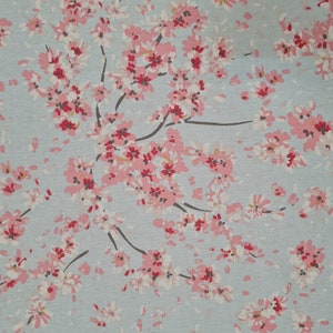 May include: A light blue fabric with a pink floral pattern. The fabric features a repeating design of small pink flowers with white centres.