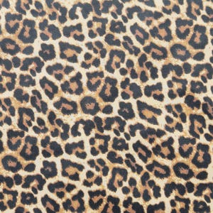 Könnte beinhalten: Nahaufnahme eines Stoffes mit Leopardenmuster. Das Muster zeigt dunkelbraune und schwarze Flecken auf beigem Hintergrund. Die Flecken variieren in Größe und Form und erzeugen ein strukturiertes Aussehen.