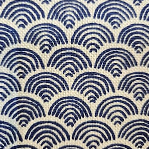 Könnte beinhalten: Nahaufnahme eines Stoffes mit einem sich wiederholenden Muster aus marineblauen Bögen auf cremefarbenem Hintergrund. Die Bögen sind in einem geschichteten, schuppenartigen Design angeordnet und erzeugen ein strukturiertes Aussehen. Der Stoff hat eine gewebte Textur.
