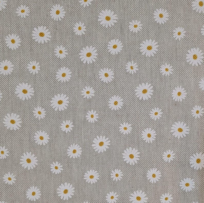 May include: A grey fabric with a white daisy pattern. The daisies have yellow centres.
