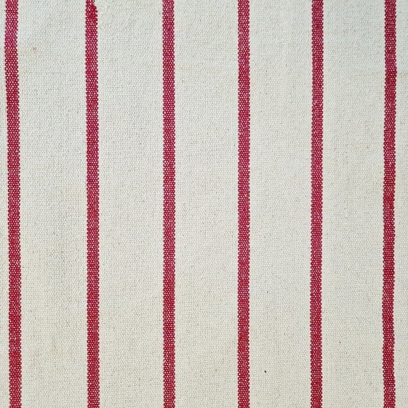 Puede incluir: Tela blanca con rayas rojas. La tela tiene una textura tejida.