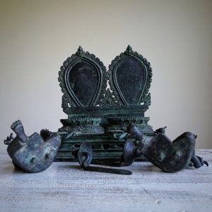 May include: A set of antique bronze Buddhist altar pieces, including a throne with two ornate seats, and four smaller figures. The pieces are intricately carved and have a dark green patina.