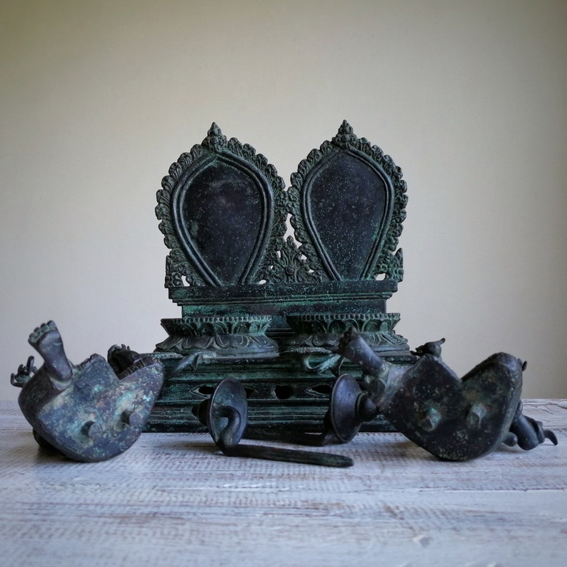 May include: A set of antique bronze Buddhist altar pieces, including a throne with two ornate seats, and four smaller figures. The pieces are intricately carved and have a dark green patina.