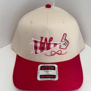 May include: A beige and red baseball cap with a red brim. The cap features a white pennant with a red gingham "W" and a hand with a raised index finger. The cap has the text "OTTO" and "MID PROFILE".