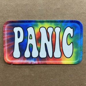 May include: A tie-dye fabric patch with the word "PANIC" in white letters.