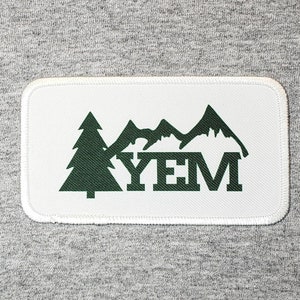 May include: White patch with green mountains and trees, with the text "YEM" in the center.