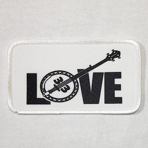 May include: White patch with black embroidered text "LOVE" with a banjo silhouette in the middle of the word.