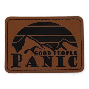 May include: A rectangular brown patch with black text and a mountain range design. The text reads "GOOD PEOPLE PANIC" in a bold, sans-serif font. The patch has a stitched border.