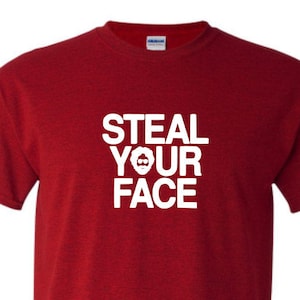 May include: Red t-shirt with white text that says "Steal Your Face" with a small graphic of a face with a beard.