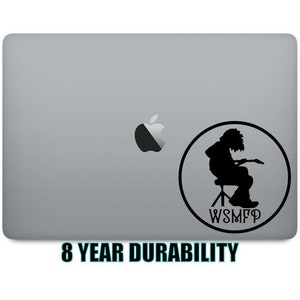 May include: A black and white sticker of a person playing guitar with the text "WSMF" on a silver laptop.