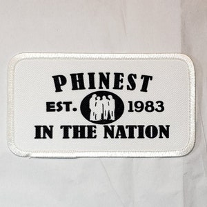 May include: White rectangular patch with black text and a silhouette of five people in a circle. The text reads "Phinest Est. 1983 In The Nation".