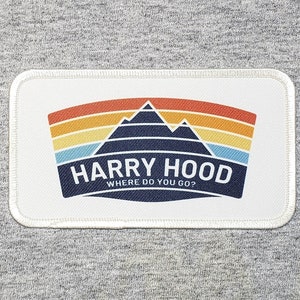 May include: White patch with a blue mountain range graphic and a sunset behind it. The text "HARRY HOOD WHERE DO YOU GO?" is below the graphic.