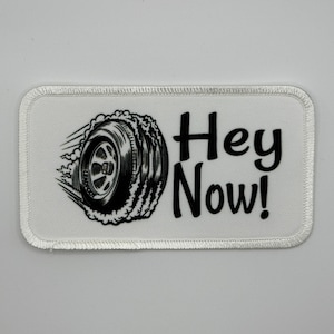 May include: White embroidered patch with a black tire design and the text "Hey Now!"