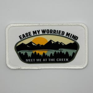 May include: White embroidered patch with a mountain scene and the text "Ease My Worried Mind Meet Me At The Creek".