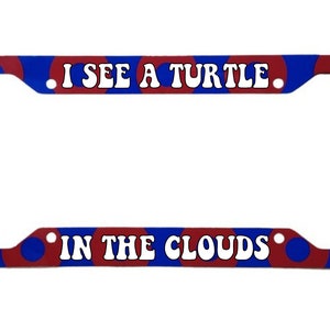 May include: A red and blue license plate frame with white text that reads "I SEE A TURTLE IN THE CLOUDS".