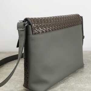 Puede incluir: Bolso bandolera gris con solapa marr&oacute;n oscuro texturizada. El bolso tiene una correa larga y ajustable y un dise&ntilde;o elegante. El bolso est&aacute; hecho de un material liso y mate.