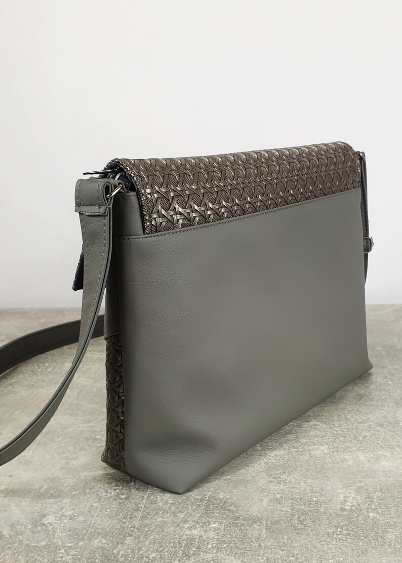 Puede incluir: Bolso bandolera gris con solapa marr&oacute;n oscuro texturizada. El bolso tiene una correa larga y ajustable y un dise&ntilde;o elegante. El bolso est&aacute; hecho de un material liso y mate.