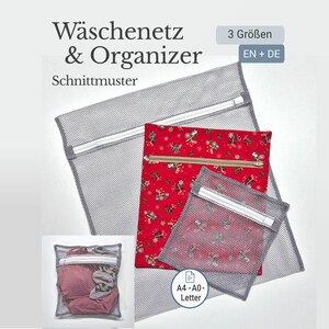 Op de afbeelding: Drie grijze waszakken van gaas met witte ritsen, waarvan één met een rood kerstpatroon. De tassen zijn gelabeld met "Wäschenetz & Organizer" en "Schnittmuster". Een kleinere tas met kleding is ook afgebeeld.