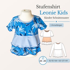 Puede incluir: Una camiseta infantil con estampado de hojas azules y blancas sobre un maniquí. La camiseta tiene un volante azul claro y el texto "Stufenshirt Leonie Kids" es visible. Diseñada para tallas EU 92-164 y US 12T-14Y.