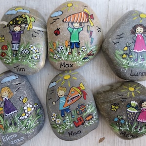 May include: Hand-painted decorative stones featuring children with school-themed illustrations. Each stone has a unique design, including children with school bags, flowers, and the names Tim, Max, Luna, Elisa, Nico, and Mona. The stones are gray with colorful artwork.