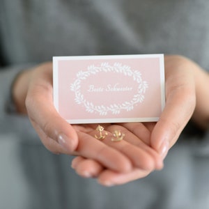 Tarjeta de regalo para hermanas más aretes de ancla en oro o plata y envoltorio de regalo con pegatina de agradecimiento.