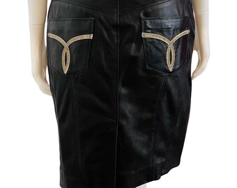 May include: Black leather skirt with gold embroidery on the back pockets. The skirt has a fitted silhouette and a straight hem.