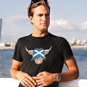 May include: A dark grey t-shirt with a brown highland cow graphic. The cow's face is replaced with the Scottish flag.