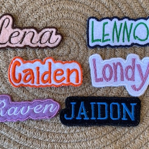 May include: Six colorful embroidered fabric patches with names spelled out in cursive lettering. The names are Lena, Lennox, Caiden, Londyn, Raven, and Jaidon.