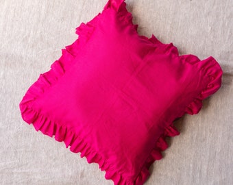 May include: A bright pink pillow with a ruffled edge. The pillow is made of a soft, cotton fabric.