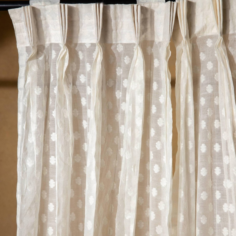 May include: White sheer curtains with a small floral pattern. The curtains are hung on a black curtain rod.