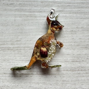 May include: A kangaroo pendant made from clear resin, filled with dried flowers and botanical elements. The kangaroo is in a standing pose with a silver-coloured bail at the top for hanging. The pendant has a natural, earthy aesthetic.