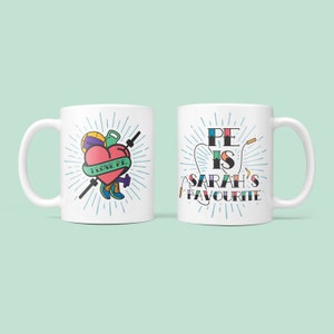 May include: Two white mugs with a colorful design. One mug has a heart with the text "I love PE" and sports equipment. The other mug has the text "PE is Sarah's favourite".