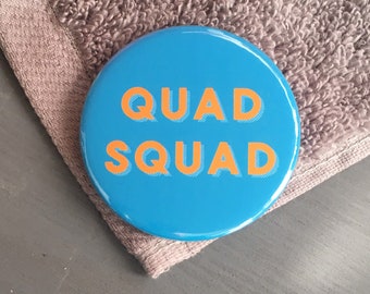 May include: A blue round button with the text "QUAD SQUAD" in orange letters.