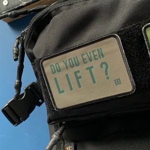 May include: Black backpack with a tan patch that says "Do You Even Lift?" in green text.