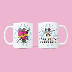 May include: Two white mugs with a blue and white design. One mug has a heart with the text "I love PE" and sports equipment. The other mug has the text "PE is SARAH'S favourite".