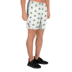 May include: White athletic shorts with a green marijuana leaf pattern. The shorts have a pink donut logo on the left leg.