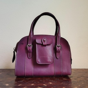 Cartera de bolsillo pequeña con doble asa de la colección Alto de Dooney & Bourke en color morado