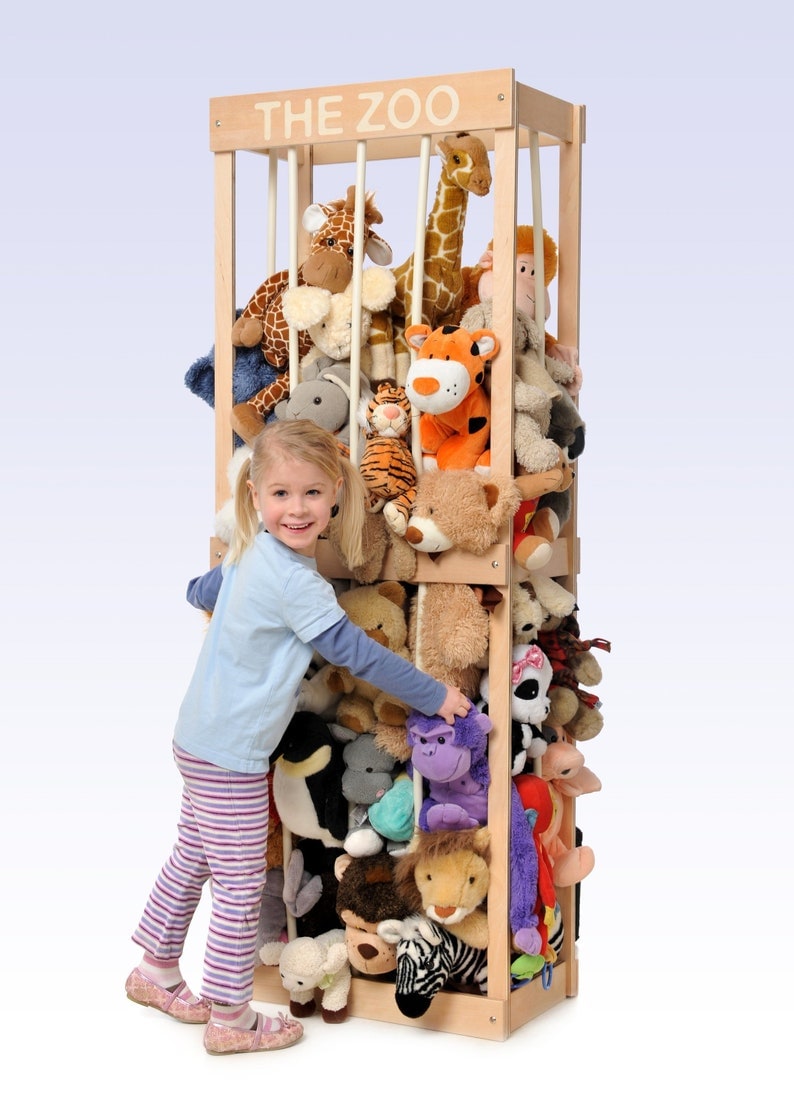 A little girl near a stuffed animal zoo full of plush toys.